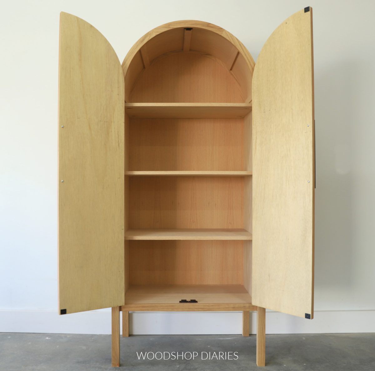 Arched cabinet with doors open to reveal shelves inside