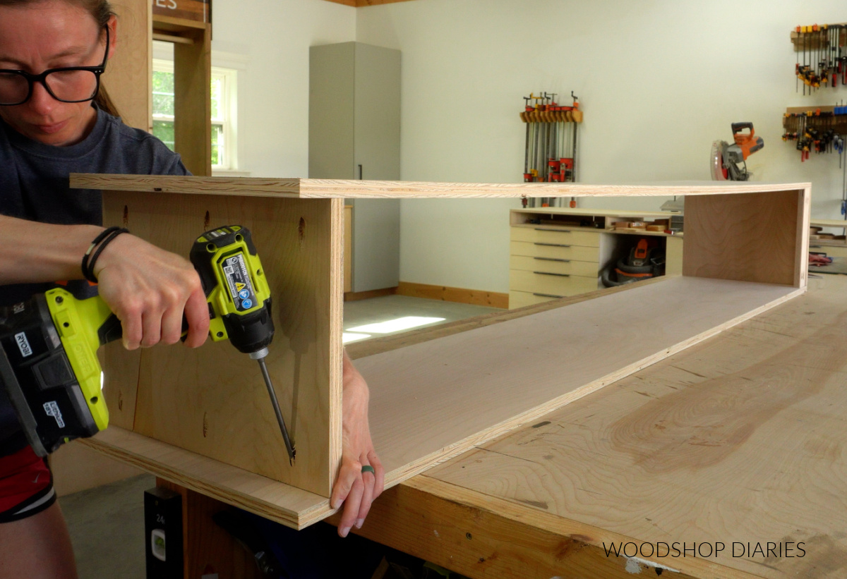 Shara Woodshop Diaries installing cabinet box bottom panel on workbench with pocket holes
