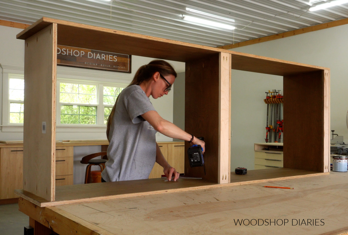 Shara Woodshop Diaries assembling large closet cabinet box on workbench with pocket holes. Cabinet has three shelves and two back support strips