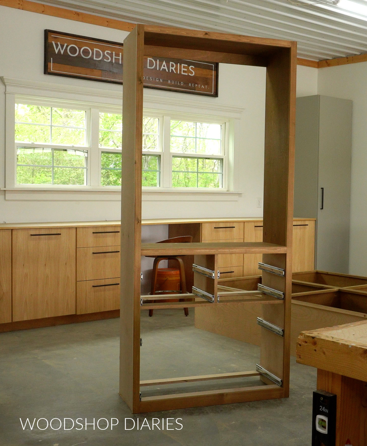 Drawer slides installed into bottom section of closet tower cabinet in workshop