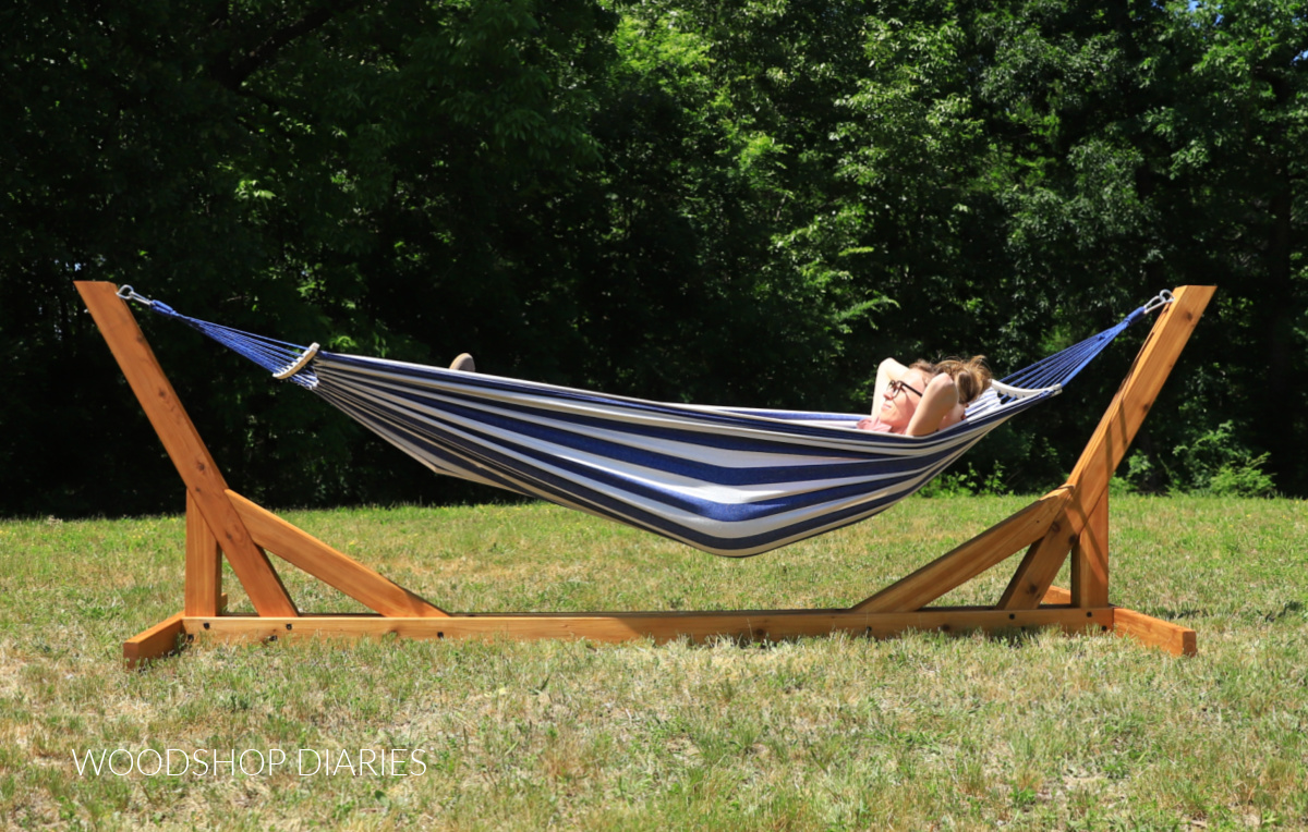 Shara Woodshop Diaries laying in blue and white hammock hanging on wooden hammock stand in backyard