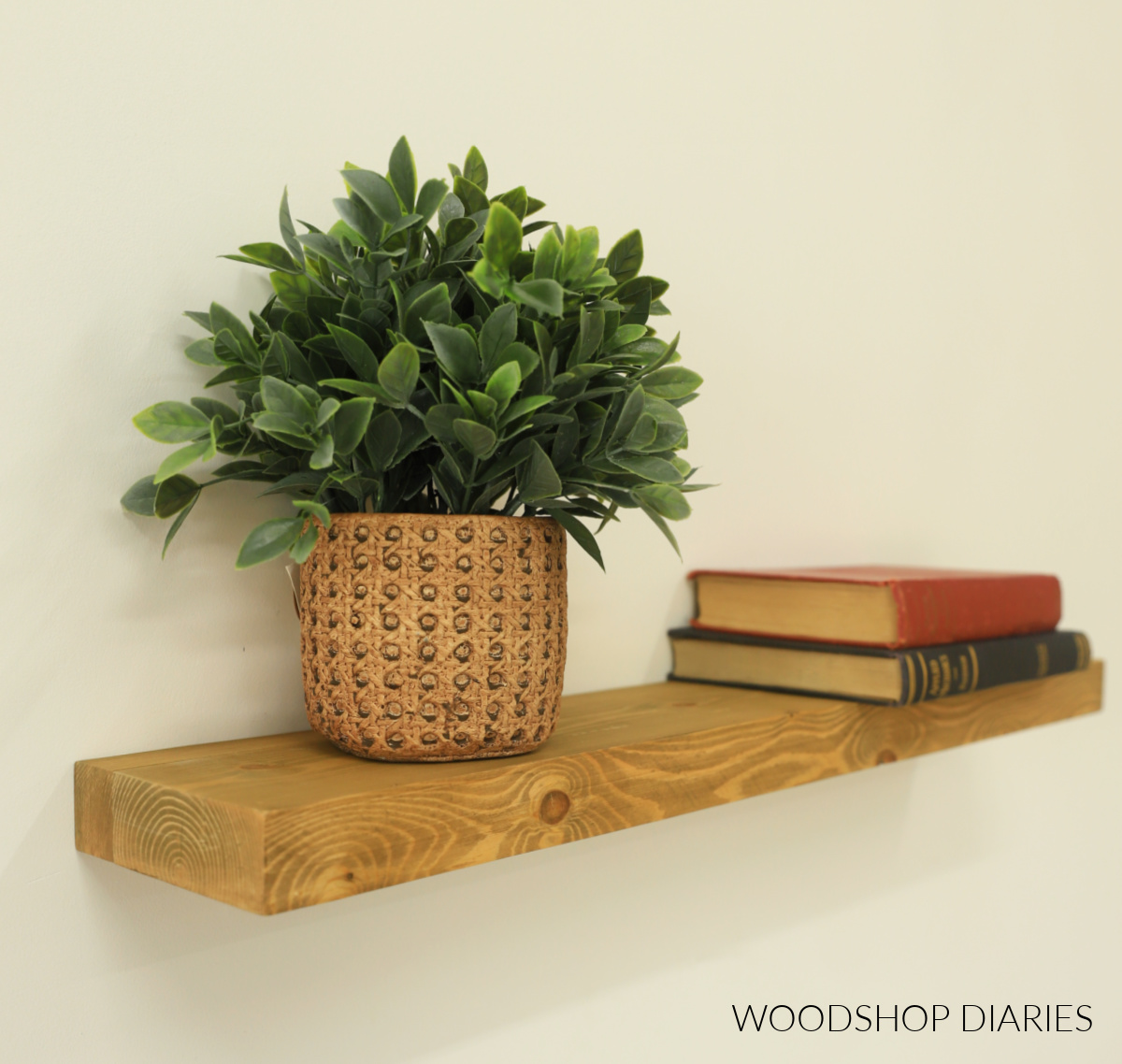 DIY wooden floating wall shelf with faux plant and stacked books