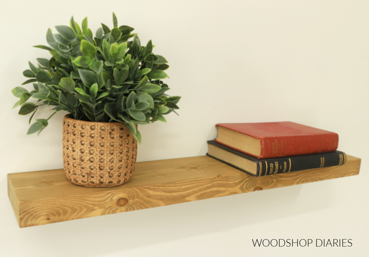 Completed minimalist DIY floating shelf made from 2x6 scraps hanging on wall