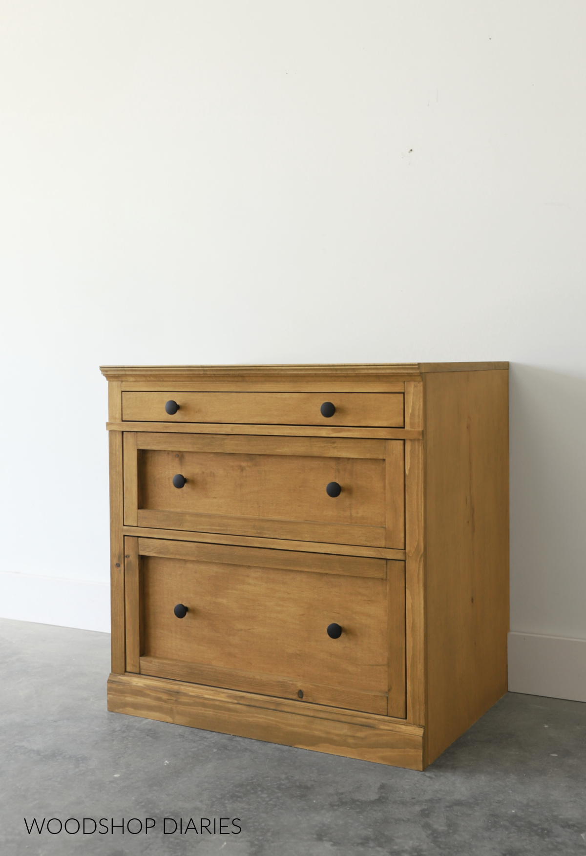 3 drawer wooden cabinet with trim detail and black knobs