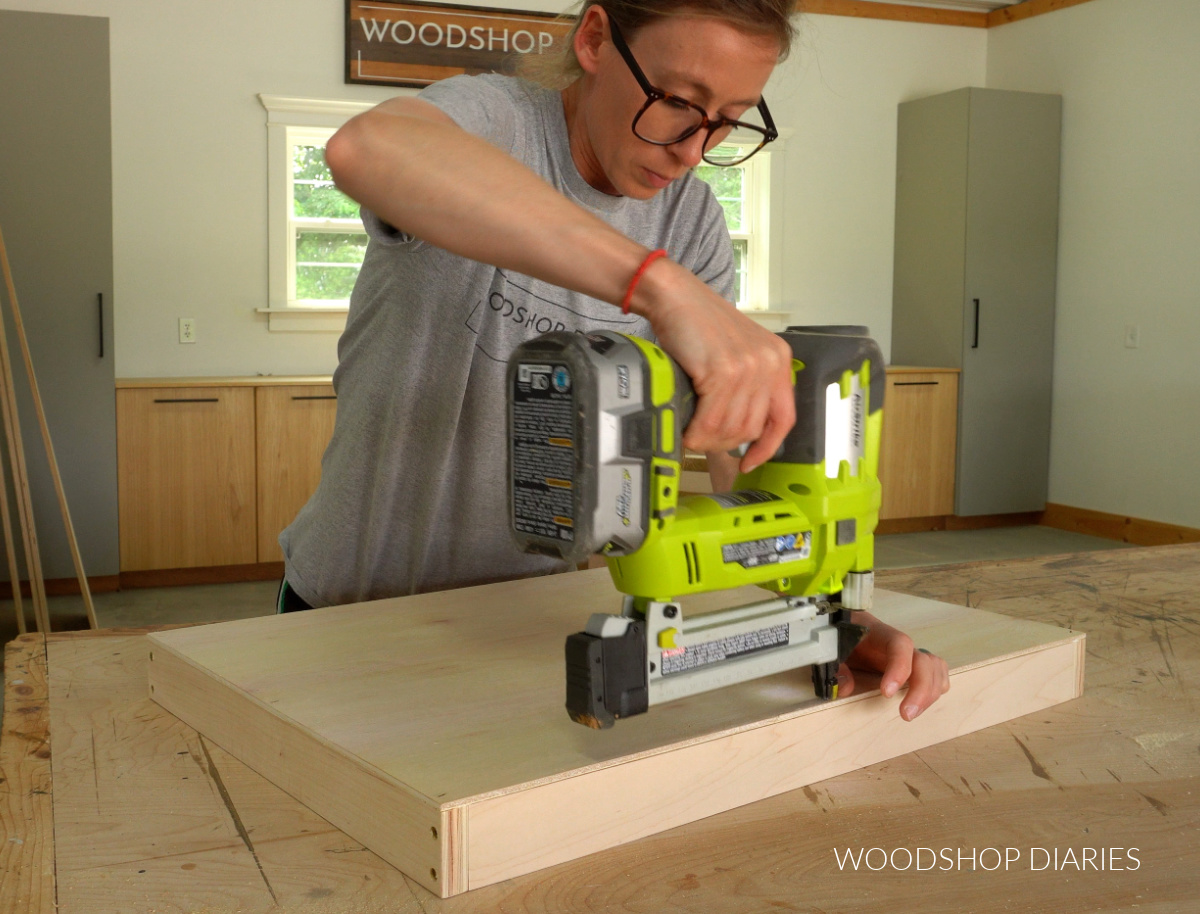 Shara Woodshop Diaries nailing bottom panel onto drawer box on workbench