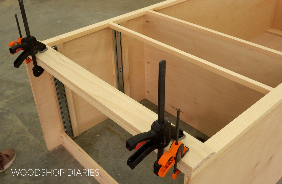 Close up of baseboard trim clamped onto bottom of cabinet