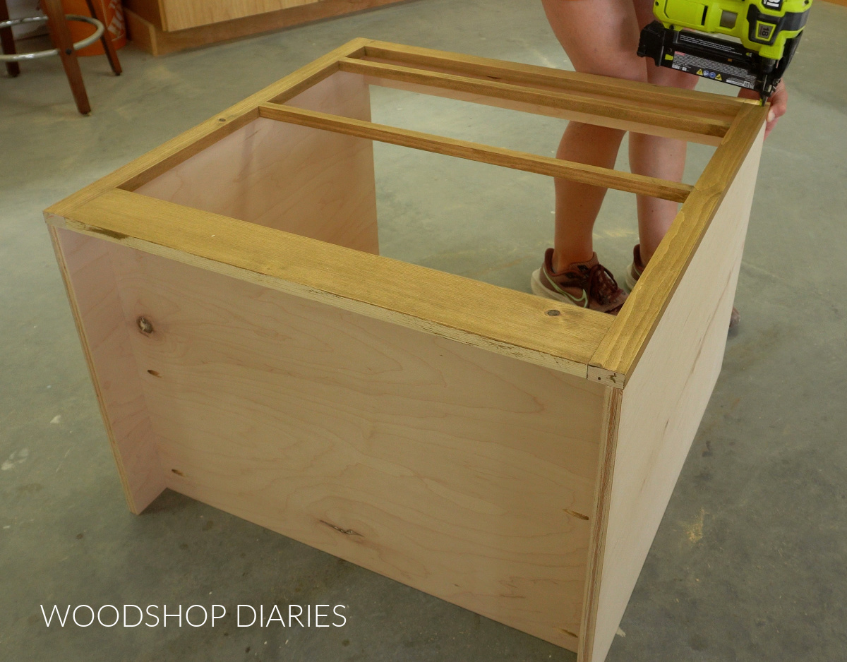 Shara Woodshop Diaries nailing face frame onto front of cabinet box on workshop floor