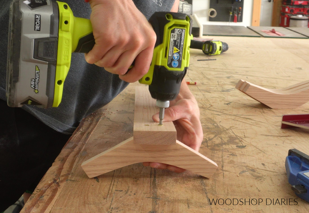 Close up of Shara Woodshop Diaries driving screws to secure hooks to towel rack