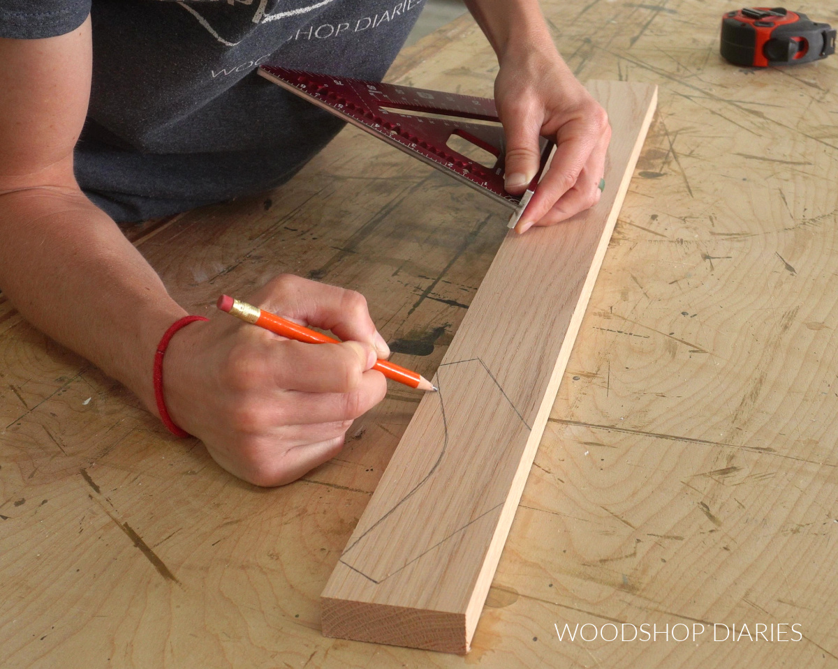 Shara Woodshop Diaries tracing towel rack hook shape onto 1x3 board on workbench