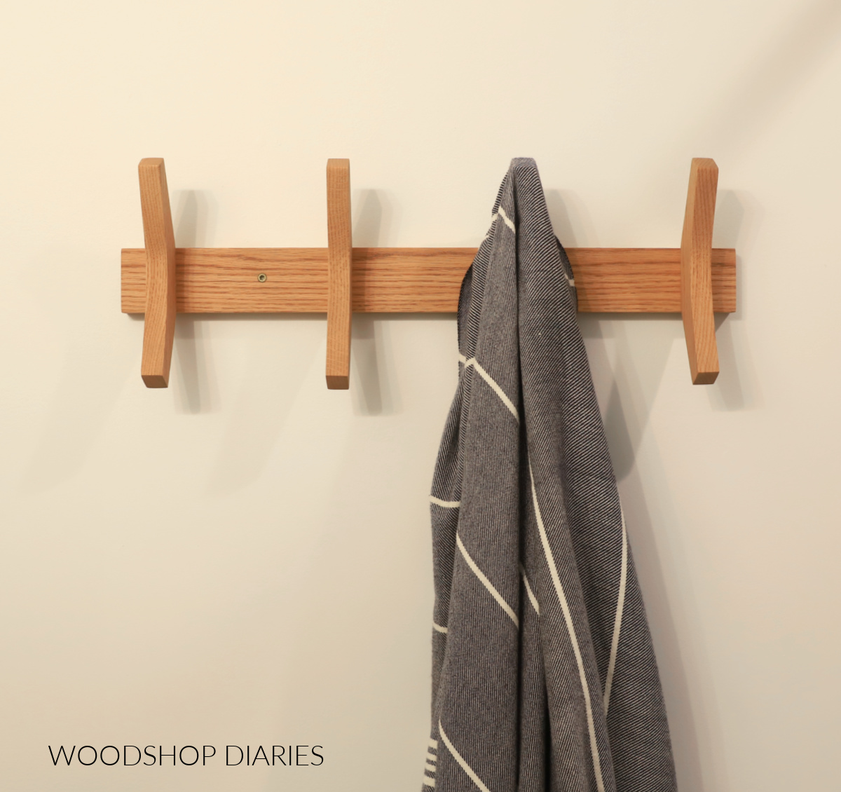 Completed DIY towel rack hanging on white wall with gray towel on hook