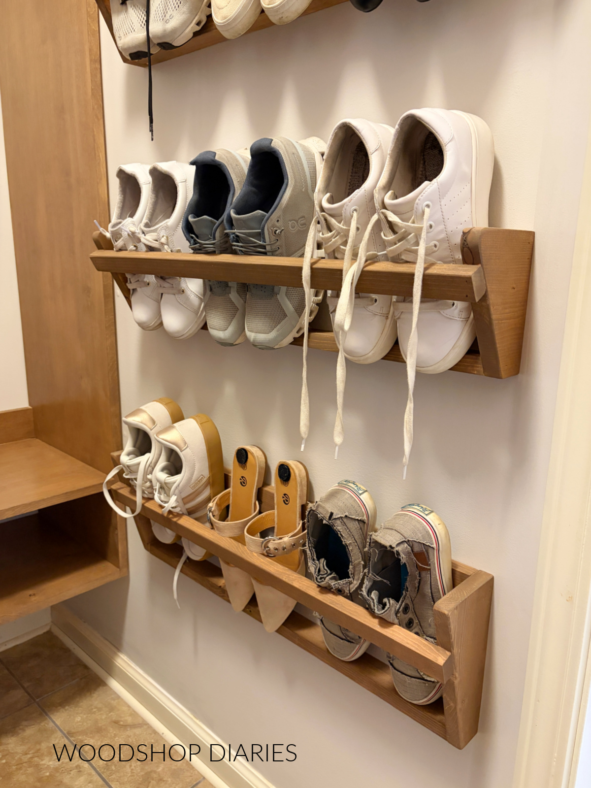 Three finished DIY shoe racks hanging on white wall with three pair of shoes stored inside each one