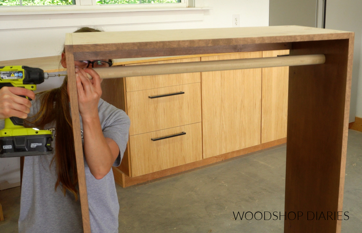 Shara Woodshop Diaries screwing dowel rod into closet cabinet for hanging clothes