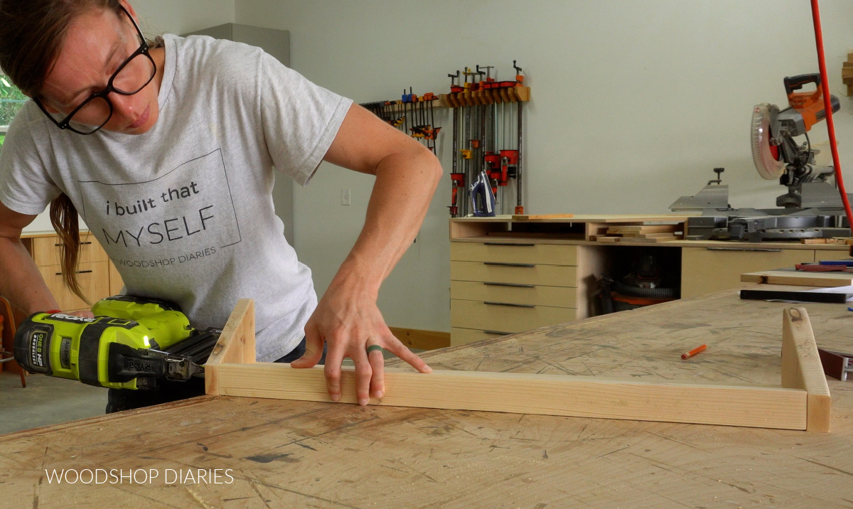 Shara Woodshop Diaries brad nailing DIY shoe rack together on workbench