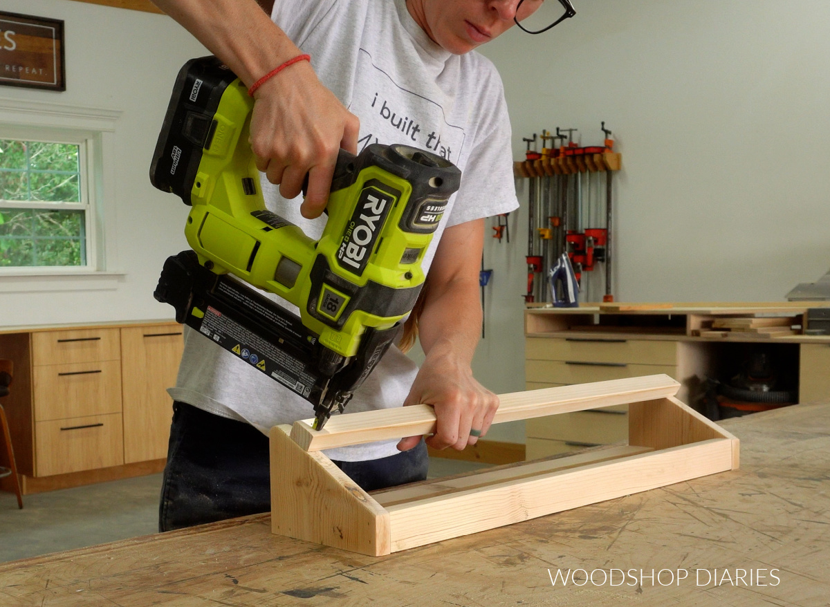 Shara Woodshop Diaries nailing front rail onto shoe rack on workbench