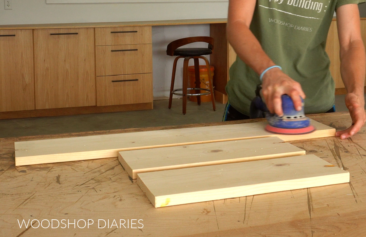 Shara Woodshop Diaries sanding 1x6 boards on workbench before assembling countertop shelf
