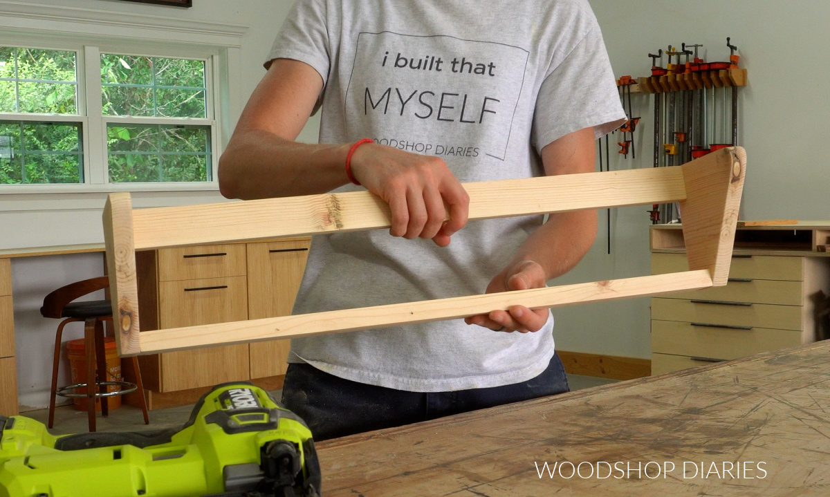 Shara Woodshop Diaries holding DIY wall mounted shoe rack partially assembled