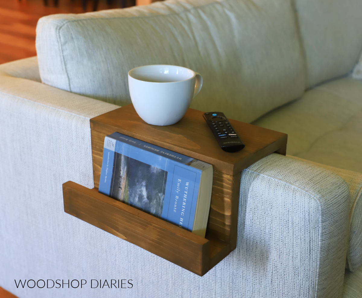 Wooden sofa arm tray with book, remote ad cup of tea on couch arm
