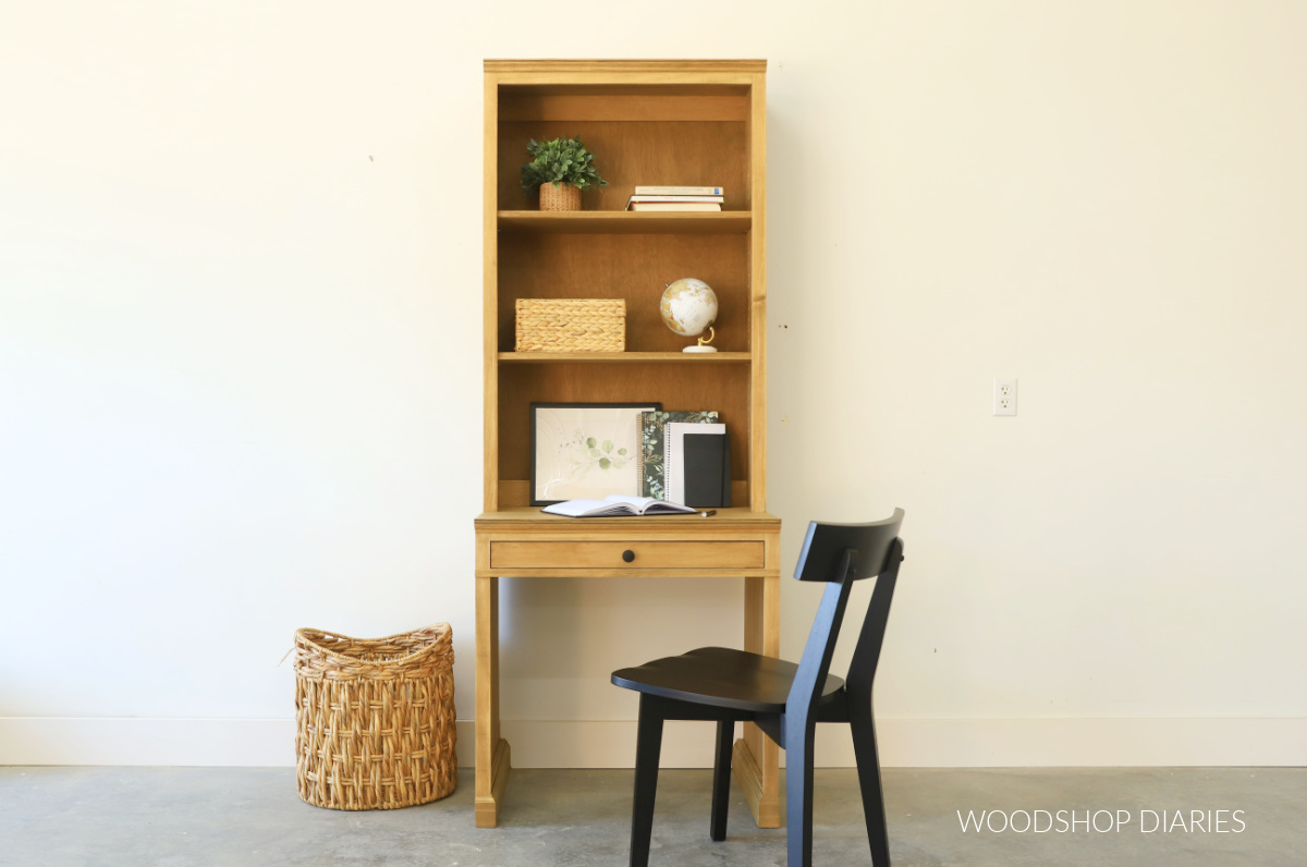 DIY Desk with Bookcase hutch completed with adjustable shelves and shallow drawer against white wall with black chair and basket