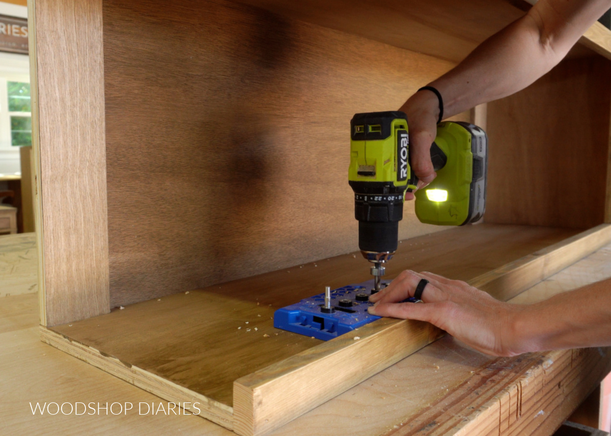 Close up of Shara Woodshop Diaries drilling shelf pin holes inside bookcase hutch cabinet