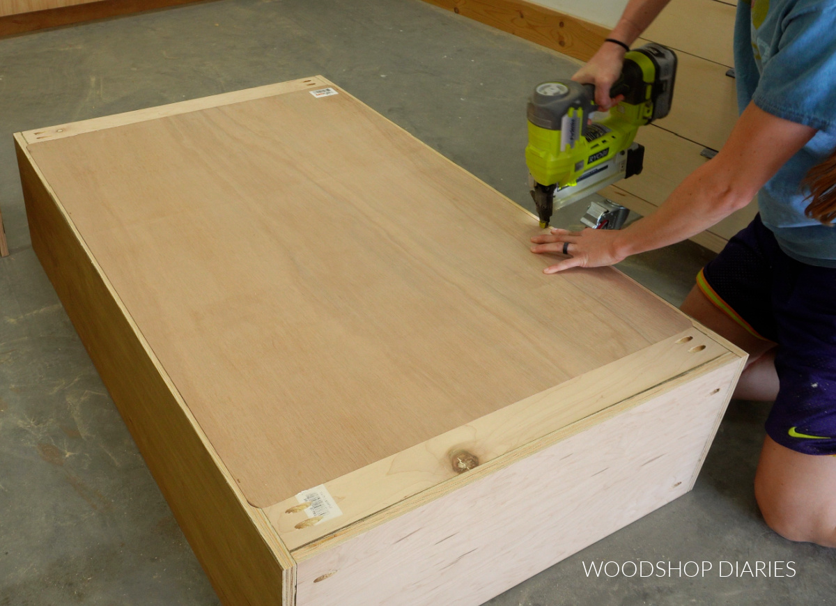 Shara Woodshop Diaries installing back panel of bookcase hutch with stapler