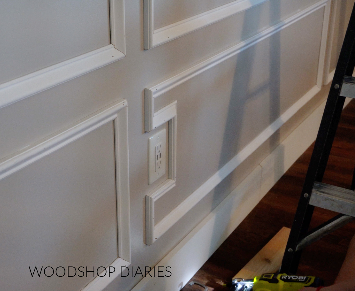 Close up of picture frame molding wrapping around outlet on bedroom wall